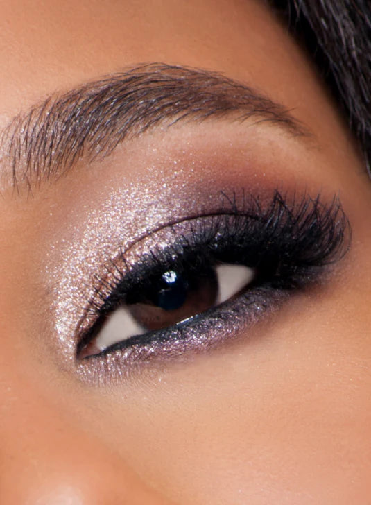 Close-up of an eye with shimmering purple eyeshadow and voluminous lashes.