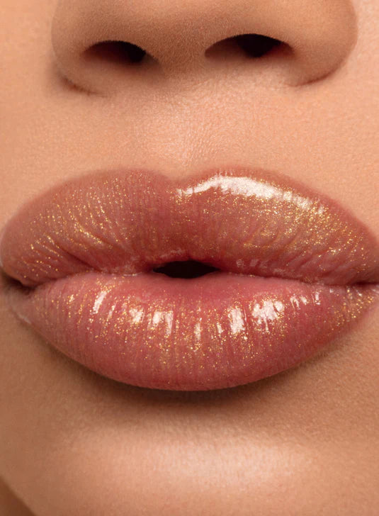 Close-up of glossy nude lips with a subtle golden shimmer.